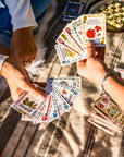 Two people playing a nature card game on a blanket outdoors