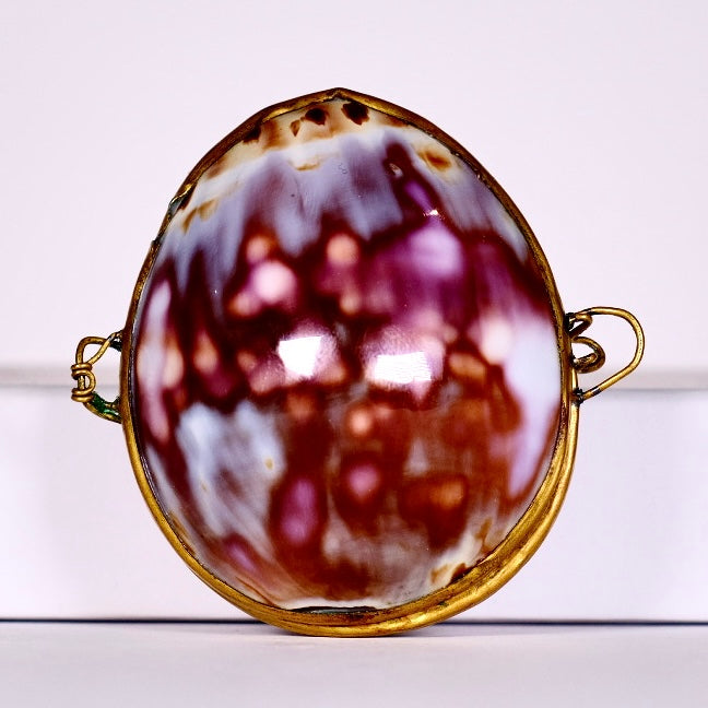 Brooch with a marbled design and gold frame on a white background