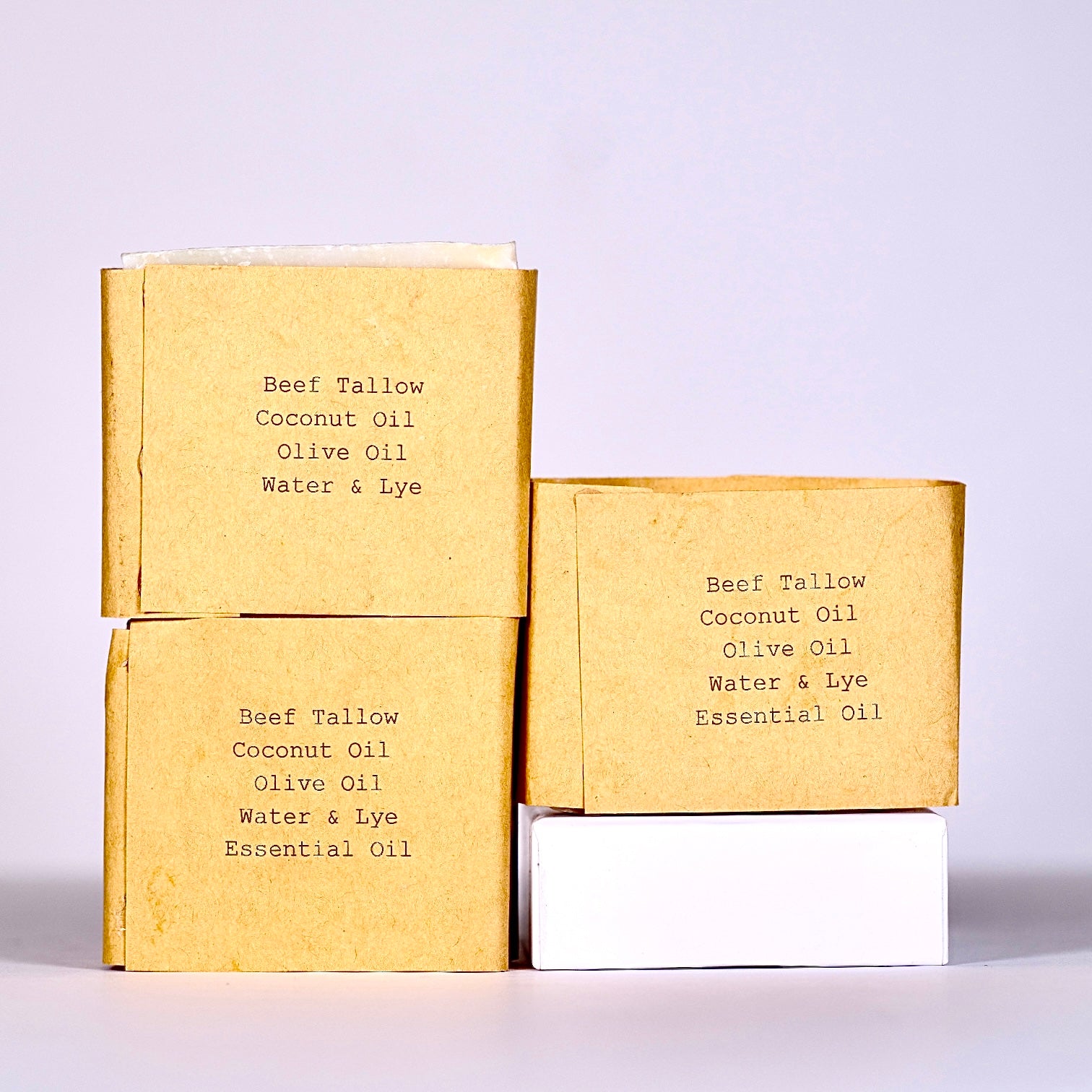 Three wrapped bars of soap with text on paper wrapper on a white background
