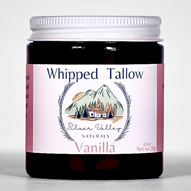 Jar of 'Whipped Tallow' vanilla product with a mountain and cabin design on the label.