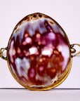 Brooch with a marbled design and gold frame on a white background