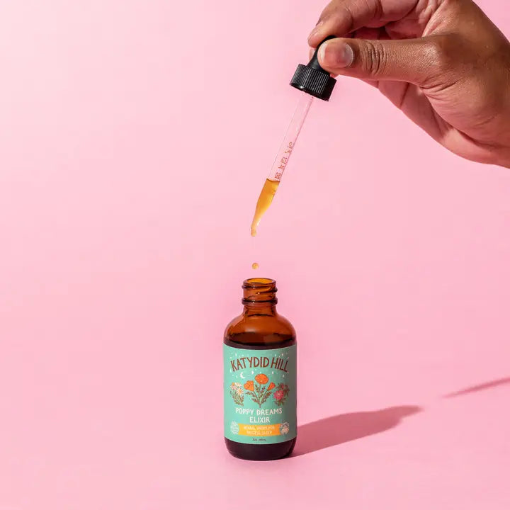 Bottle of Poppy Dream Elixir with hand holding dropper above.