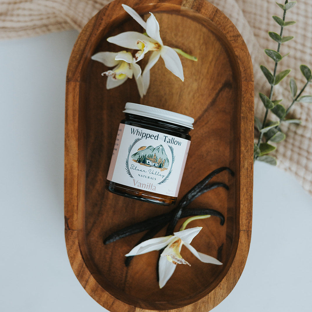 Jar of &#39;Whipped Tails&#39; with vanilla beans and flowers on a wooden tray